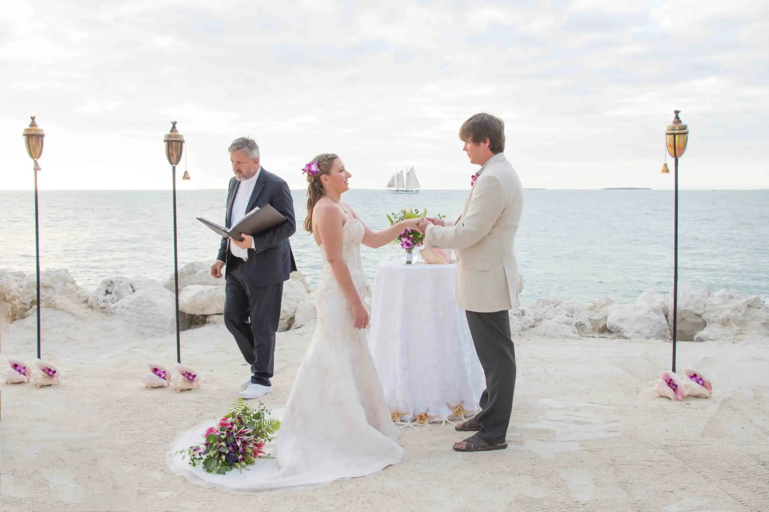 Key West wedding planners create customized key west wedding packages as a bride and groom exchange vows in front of the ocean.