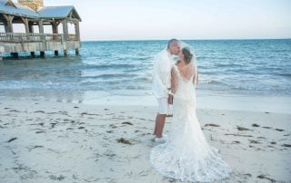 A bride and groom exchanging vows on the beach near a pier, captured beautifully by a skilled Key West wedding photographer.