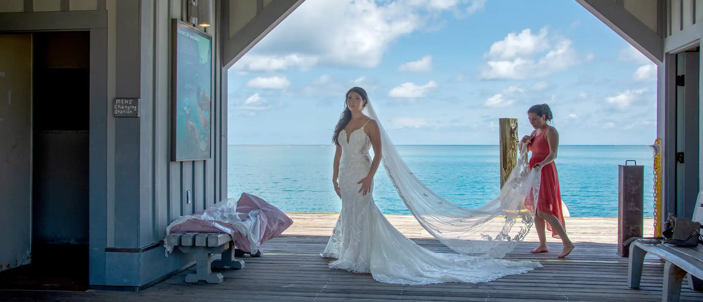 A bride and her bridesmaid are standing on a dock near the ocean for their Key West wedding.