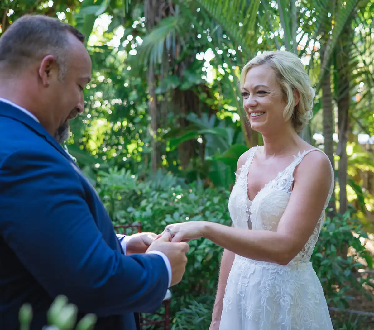 A bride and groom exchanging their wedding rings in a garden with the assistance of a key west wedding officiant.
