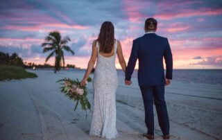 A beautiful couple, captured by a talented Key West wedding photographer, strolling hand in hand along the picturesque beach at sunset.