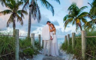 A bride and groom standing on a wooden walkway near palm trees, captured beautifully by a talented Key West wedding photographer.