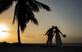 A bride and groom are silhouetted on the beach at sunset during their Key West wedding ceremony.
