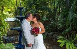 A bride and groom share a tender kiss in front of a mesmerizing fountain during their romantic Key West wedding.