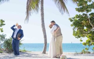 A romantic bride and groom sharing a passionate kiss during their Key West beach wedding.