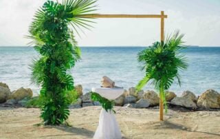 A stunning palm tree wedding arch on the beach, perfectly coordinated by Key West wedding planners.