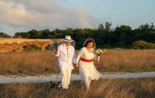 A couple walking through a field with their dog during their Key West wedding.
