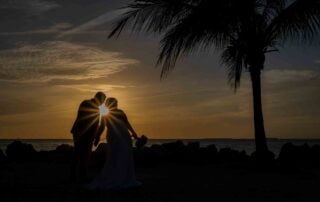 Silhouetted bride and groom exchange vows on the beach at sunset, captured by a talented Key West wedding photographer.