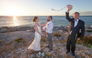 A bride and groom standing on a beach with a kite in the air, captured beautifully by a talented key west wedding photographer.