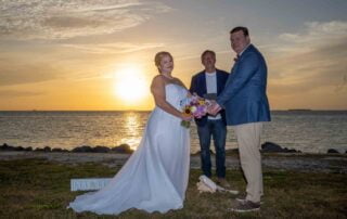 A bride and groom having their picture taken in front of the ocean at sunset by a Key West wedding photographer.