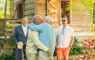 A group of men embracing affectionately in front of a house, captured beautifully by a talented key west wedding photographer.