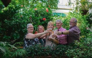 A group of people toasting in a garden during their Key West wedding celebration.