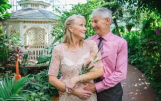 A key west wedding officiant and key west wedding photographer capture an older couple posing in front of a gazebo in a greenhouse as part of their key west wedding package.