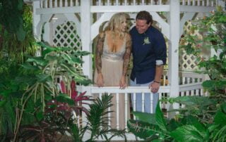 A bride and groom standing in front of a gazebo in a tropical garden, captured beautifully by a talented Key West wedding photographer.