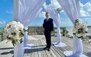 A man in a suit standing on a wooden boardwalk during a Key West wedding.
