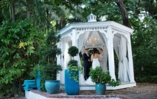 A bride and groom standing in front of a beautiful gazebo, surrounded by the tropical beauty of Key West.