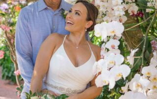 A bride and groom posing in front of orchids in a garden for their Key West wedding.