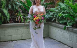 A bride in a white dress standing in a courtyard with tropical plants captured by a key west wedding photographer.