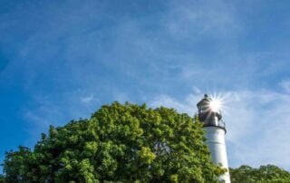 A picturesque lighthouse overlooking lush trees and a radiant blue sky, perfect for unforgettable Key West wedding packages and captured by a skilled Key West wedding photographer.