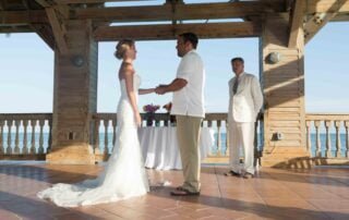 A bride and groom exchange vows on a wooden deck overlooking the ocean with the assistance of a key west wedding officiant.