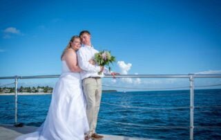 A bride and groom posing on the deck of a boat during their Key West wedding.