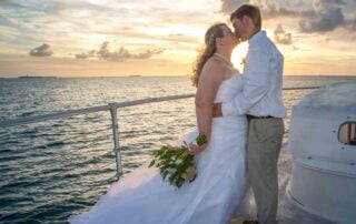 A bride and groom passionately kiss on the bow of a boat at sunset, capturing the essence of their magical Key West wedding.