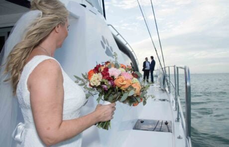 A bride and groom holding hands on the bow of a boat, captured beautifully by a key west wedding photographer.