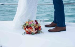 A bride and groom happily posing on the bow of a boat, captured beautifully by a skilled Key West wedding photographer.