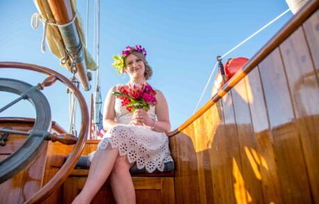 A woman sitting on the steering wheel of a wooden boat, capturing the essence of a picturesque Key West wedding ceremony.