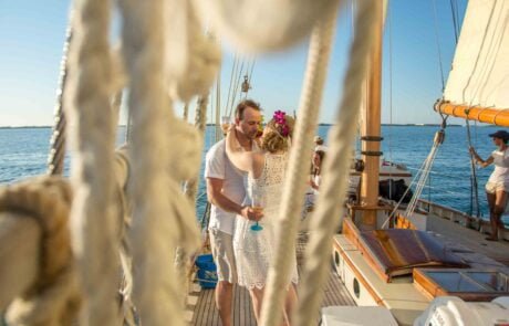 A couple sharing a romantic kiss on the deck of their sailboat during their Key West wedding ceremony.