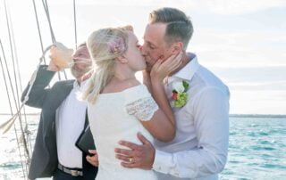 A bride and groom share a loving kiss on the bow of a sailboat during their unforgettable Key West wedding.