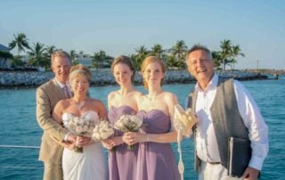 A group of bridesmaids and groom pose on a boat while capturing the magical moments of their Key West wedding.