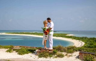 A breathtaking view of a bride and groom on top of a hill, exchanging vows with the vast ocean as their backdrop.