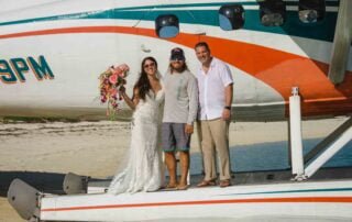 A beautiful bride and groom posing in front of a small plane, captured by a talented Key West wedding photographer.