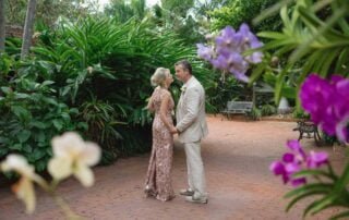 A bride and groom standing in a garden with orchids during their Key West wedding.